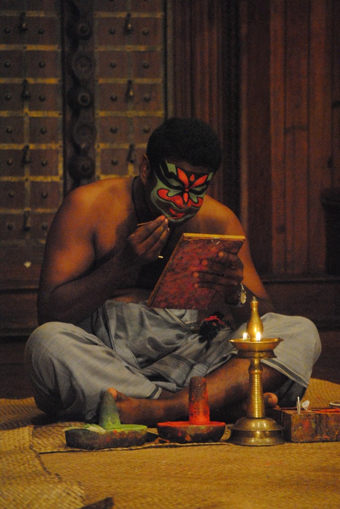 A Kathakali actor applies his makeup. He later needed help gluing part of his costume to his face.